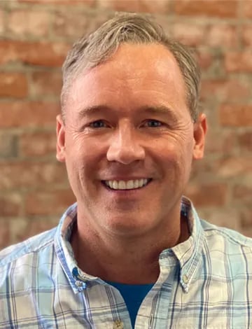Jason Thrasher smiling in a plaid shirt.