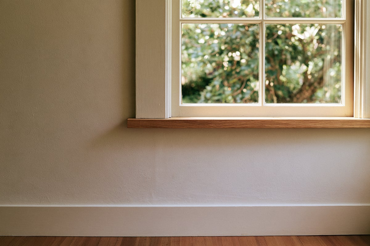 Illustrative painted window frame, wood sill, and softly lit plaster wall.